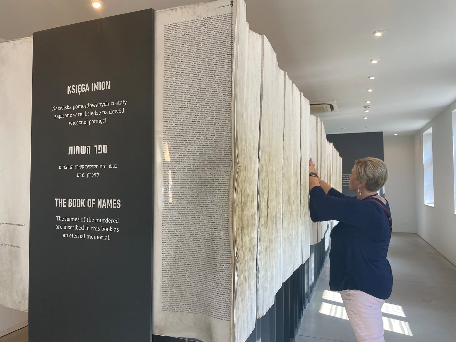 Helias Catholic High School teacher Kathy Jarman searches through the Book of Names in Auschwitz I, which lists the known names of those who were killed during the Holocaust.
